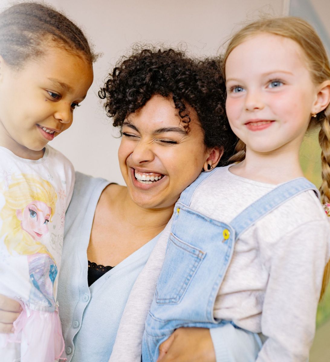 Educadora sonriendo junto a dos niñas